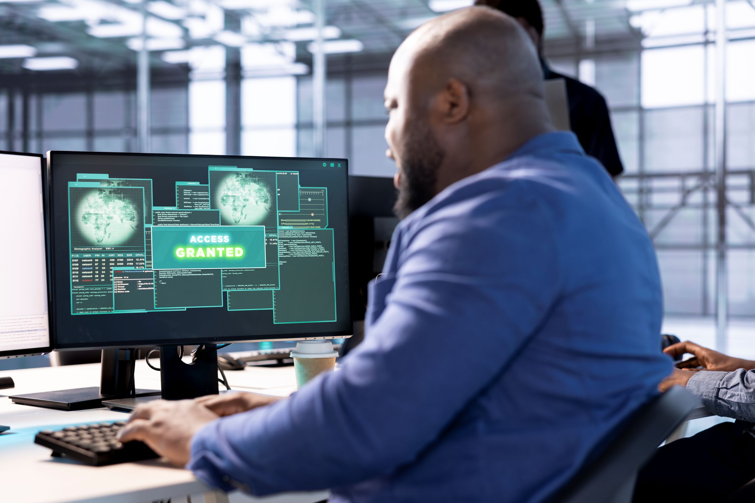 IT professional at desk with computer screen showing 'Access Granted' in a modern office.